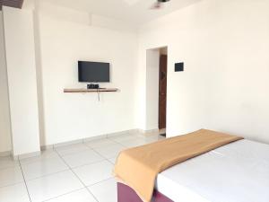 a bedroom with a bed and a tv on a wall at Hotel Jagdamb Kolhapur in Kolhapur