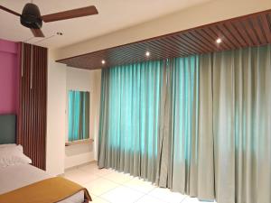 a bedroom with a large window with blue curtains at Hotel Jagdamb Kolhapur in Kolhapur