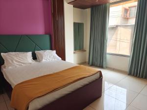 a bedroom with a large bed and a window at Hotel Jagdamb Kolhapur in Kolhapur