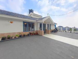 a white house with a patio with plants at QUEENS COTTAGE - individual cottage in Ooty