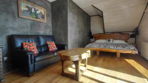 a living room with a leather couch and a bed at Apartament Huba in Huba