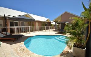 a swimming pool in a yard next to a house at Gecko Lodge Kalbarri in Kalbarri