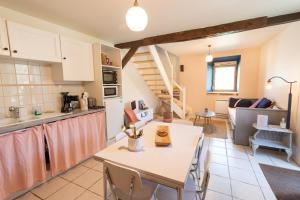 a kitchen and living room with a table and a kitchen and a staircase at Le petit ordinaire in Le Cours