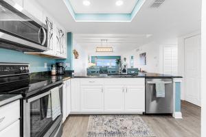 a kitchen with white cabinets and stainless steel appliances at Boardwalk 205 in Cocoa Beach