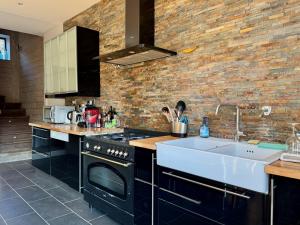 a kitchen with a black stove and a sink at Gîte Terrasse à Solutré-Pouilly in Solutré-Pouilly