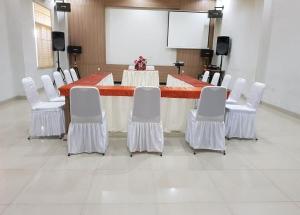 a conference room with a long table and white chairs at Miracle Hotel Manado in Manado