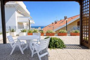 a white table and chairs on a patio with the ocean at Attico Zamagna in Cesenatico