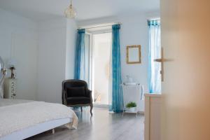a bedroom with a bed and a chair and a window at Hôtel de la Béroche in Saint Aubin Sauges