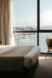 a bedroom with a view of a marina through a window at Le Nautica Hôtel in Perros-Guirec