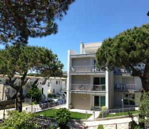 um prédio de apartamentos com árvores em frente em One-Bedroom Apartment Rosolina Mare near Sea 4 em Rosolina Mare