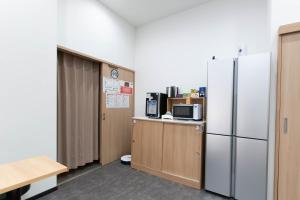 a kitchen with a refrigerator and a counter with a microwave at guest house B in Osaka