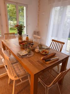 a wooden table with food on it in a room with windows at La Pause Normande - Bed & Breakfast in Bayeux +6 photos