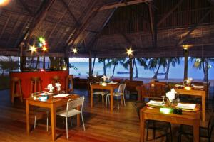 a restaurant with tables and chairs and a view of the ocean at Eden Lodge in Nosy Be