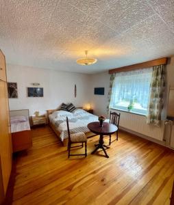 a bedroom with a bed and a table and a window at Strand Haus Am Walde in Trassenheide