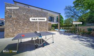a ping pong table in front of a brick building at Villa Bellissima Malinska - Privater Pool, 4 Schlafzimmer, ruhige Lage in Malinska