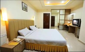 a bedroom with a large white bed and a telephone at Hotel Sitara Grand, KPHB in Hyderabad