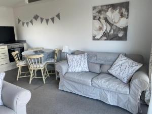 a living room with a gray couch and a table at Chalet Thirty Two in Seaton