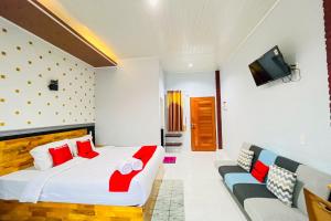 a bedroom with a large bed and a couch at RedDoorz at Hotel Dieng Berastagi in Berastagi