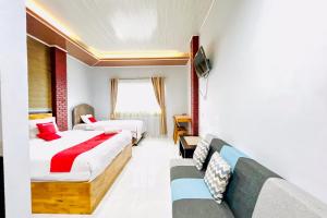 a hotel room with two beds and a couch at RedDoorz at Hotel Dieng Berastagi in Berastagi