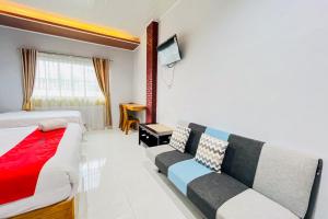 a hotel room with a bed and a couch at RedDoorz at Hotel Dieng Berastagi in Berastagi