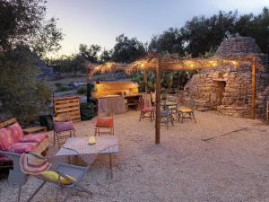 a patio with chairs and a table and a stone fireplace at Wishne Glamping Agriturismo in tende Bisceglie in Bisceglie