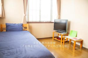a bedroom with a bed and a tv on a table at 民泊よこてこよ in Yokote