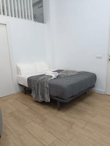 a bed in a white room with a wooden floor at RockSide Residences Suites La Línea VII in La Línea de la Concepción +2 photos