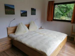 a bedroom with a bed with white sheets and a window at Gästehaus Gruber in Pusterwald