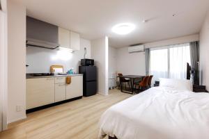 a bedroom with a bed and a kitchen with a table at Anecis笠取町2 in Nagoya