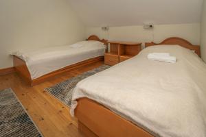 two beds in a room with wooden floors at Rév-Panzió in Abádszalók