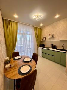 a kitchen with a wooden table and chairs in a room at A-Six Apartment, ЖК Достар 26 in Karagandy
