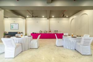 a room with two tables and white chairs and a red table at Treebo Aashirwad Bliss Inn With Swimming Pool in Jaipur