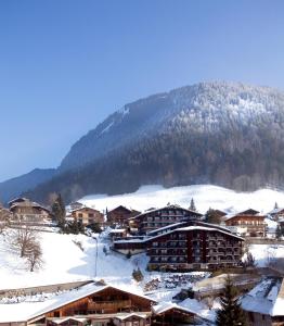 eine schneebedeckte Stadt mit einem Berg im Hintergrund in der Unterkunft Hotel le Petit Dru in Morzine