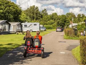 two children riding a toy car down a road at DCU-Camping Hesselhus in Silkeborg +5 photos