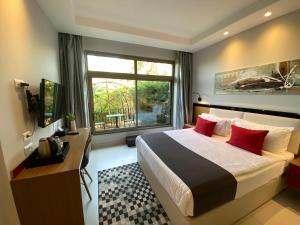 a bedroom with a bed with red pillows and a window at The Ray Hotel and Studios in Beirut