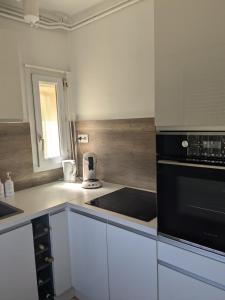 a kitchen with white cabinets and a black appliance at Maison 5 chambres front de mer classée 3 étoiles tourisme in Narbonne