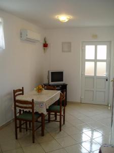 uma sala de estar com uma mesa e cadeiras e uma televisão em One-Bedroom Apartment in Senj III em Nehaj