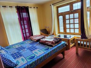 a bedroom with a bed and a desk and windows at KC Homestay in Sissu