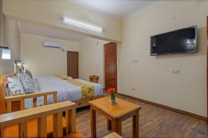 a bedroom with a bed and a tv on the wall at By the Lakeside in Bhīm Tāl