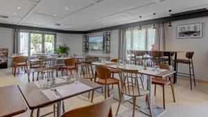 a dining room with tables and chairs and windows at Campanile NATURE - Vierzon in Vierzon