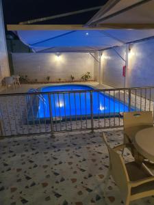 a swimming pool at night with a table and chairs at Villa Ar Rayis Beach in Rayyis