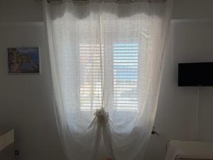 a window with white curtains in a room at Il Cirismiro in Torre Faro +26 photos
