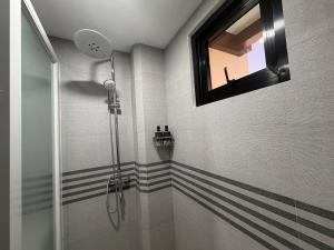 a bathroom with a shower with a mirror and a window at Apples&Pears Hotel in Manaoag +3 photos