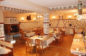 a restaurant with tables and chairs and a fireplace at Hotel Boyanovi in Bansko