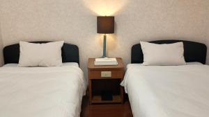 two beds in a hotel room with a lamp on a night stand at Hotel-澄Sumi-波の上ビーチ徒歩5分 in Naha