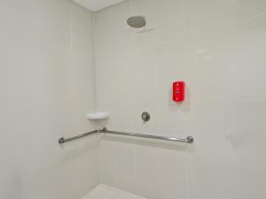 a white bathroom with a shower with a red button at Red Planet Cagayan De Oro in Cagayan de Oro