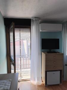 a room with a window with a television and a dresser at home sweet home in Buia