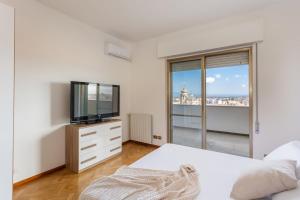 a white bedroom with a tv and a bed at Penthouse Magic View - Large penthouse in the center in Oristano