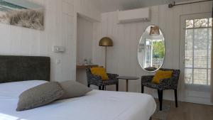 a bedroom with a bed and a mirror and a table at L'Ile sous le Vent in Sainte-Marie-de-Ré