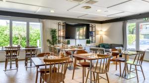 a restaurant with tables and chairs in a room with windows at Campanile NATURE - Biarritz in Biarritz